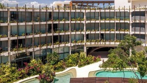 Um hotel com vários andares, varandas, área de piscina e paisagismo exuberante.
