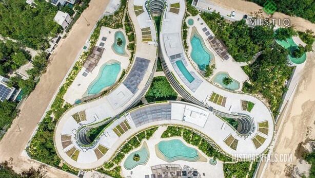 Vista aérea de um resort com várias piscinas, caminhos sinuosos e vegetação exuberante.