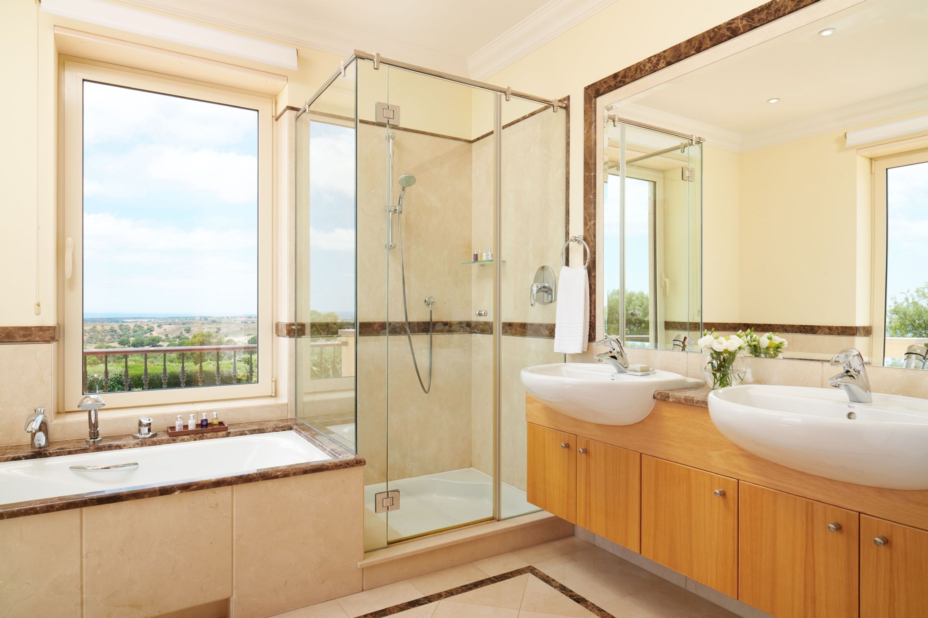 Une salle de bain moderne avec deux lavabos, une douche à l’italienne en verre et un grand miroir.