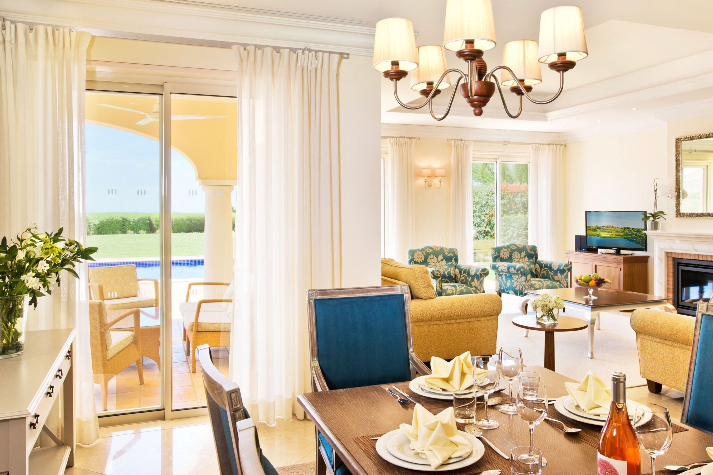 A hotel room with a dining area, a sofa set, a television, and a fireplace.