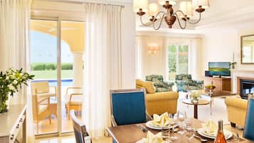A hotel room with a dining area, a sofa set, a television, and a fireplace.