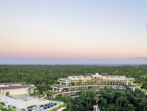 A modern resort with a central building surrounded by lush greenery and a pool area. - Top Floor Studio with Stunning Views and Balcony (Tulum)