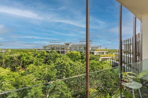Un bâtiment moderne doté de grandes fenêtres et d’un balcon donnant sur un paysage verdoyant et luxuriant.