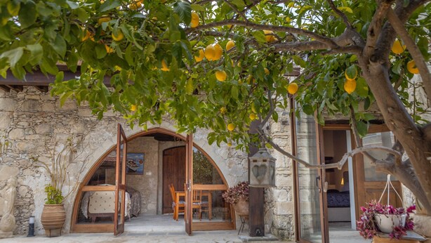 Un edificio de piedra con un arco de entrada que da a una habitación con una cama y una mesa.