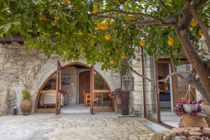 A stone building with an arched doorway leading to a room with a bed and a table. - Casale Xenia in Filousa (Filousa)