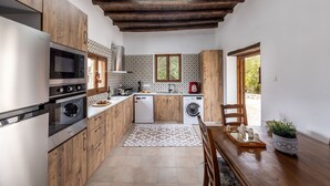 Cocina compacta con armarios de madera, refrigerador de acero inoxidable, horno, microondas, lavavajillas y lavadora.
