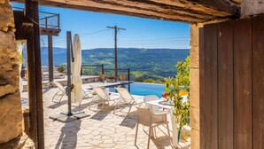 Un patio de piedra con mobiliario exterior, una piscina y vistas al paisaje.