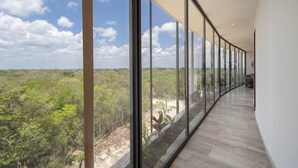 A corridor with large windows offering a view of a forested landscape. - Unique unit, private pool, terrace, views! (Tulum)