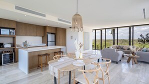 A modern kitchen with a central island, wooden bar stools, and a dining table with placemats. - Unique unit, private pool, terrace, views! (Tulum)