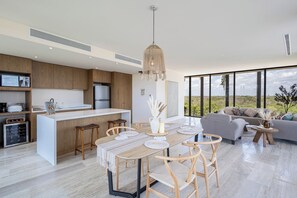 A modern kitchen with a central island, wooden bar stools, and a dining table with placemats. - Unique unit, private pool, terrace, views! (Tulum)