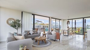 A spacious living area with a sofa, coffee table, and dining table, large windows with a view of a pool and buildings, and a decorative mirror. - Unique unit, private pool, terrace, views! (Tulum)