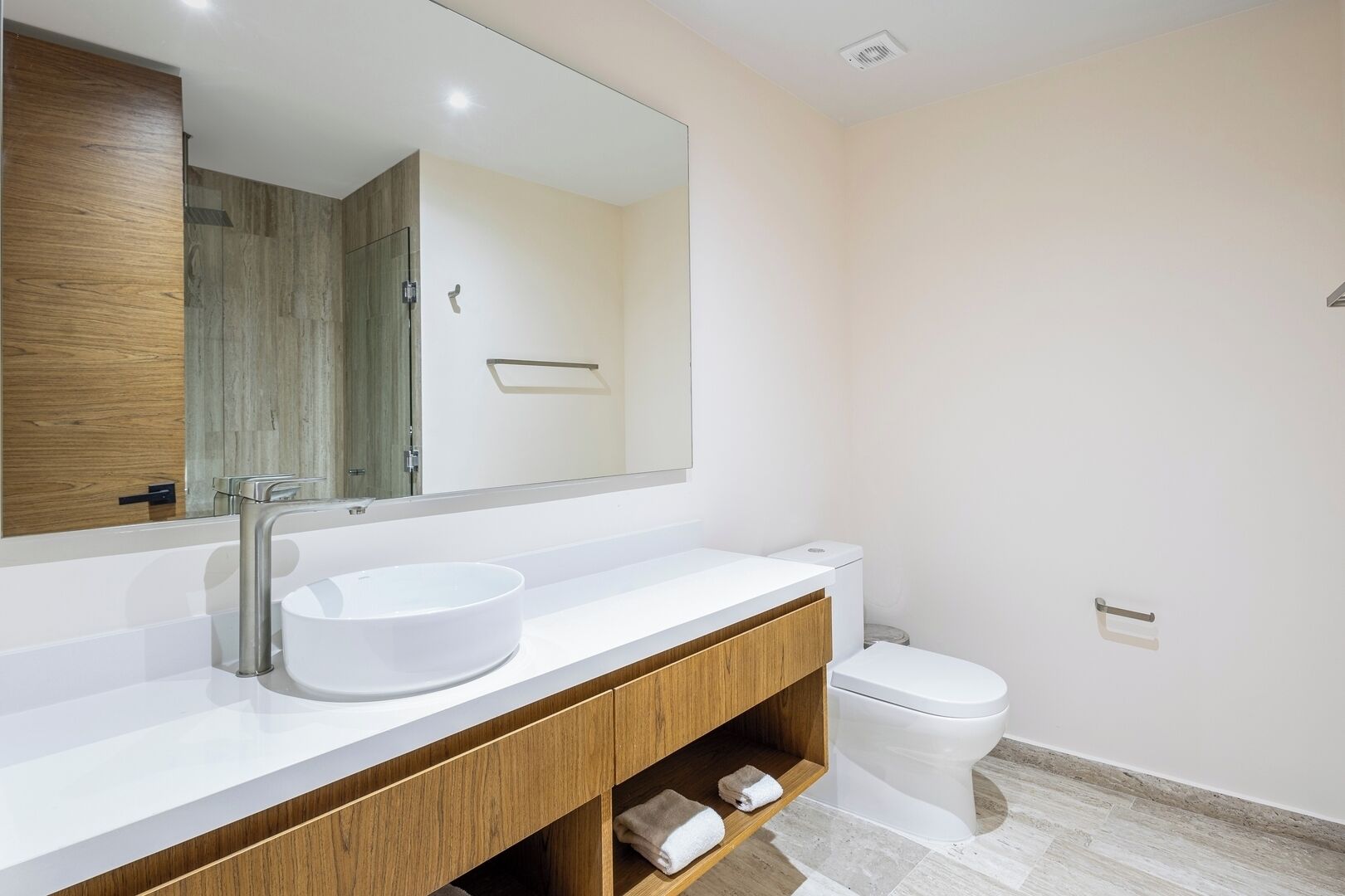 A modern bathroom with a white sink, wooden vanity, and a toilet.
