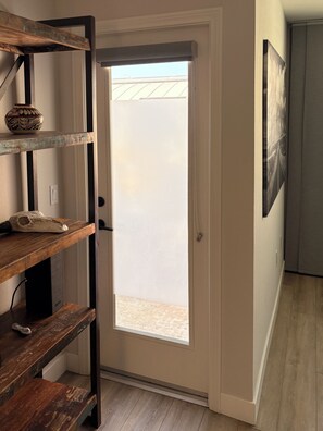 A hallway with a wooden bench, a door with a view to the outside, and a framed picture on the wall. - Coastal Living in Encinitas - Steps to Beach - 3 BR Sleeps 6 (Encinitas)