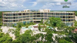 Een meerhoog hotel met een centrale binnenplaats, omgeven door weelderige begroeiing.