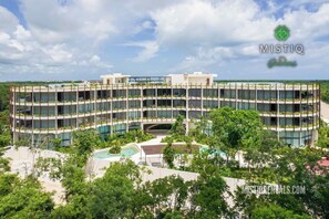 A multi-story hotel with a central courtyard, surrounded by lush greenery. - Tulum retreat at Mistiq Gardens (Tulum)