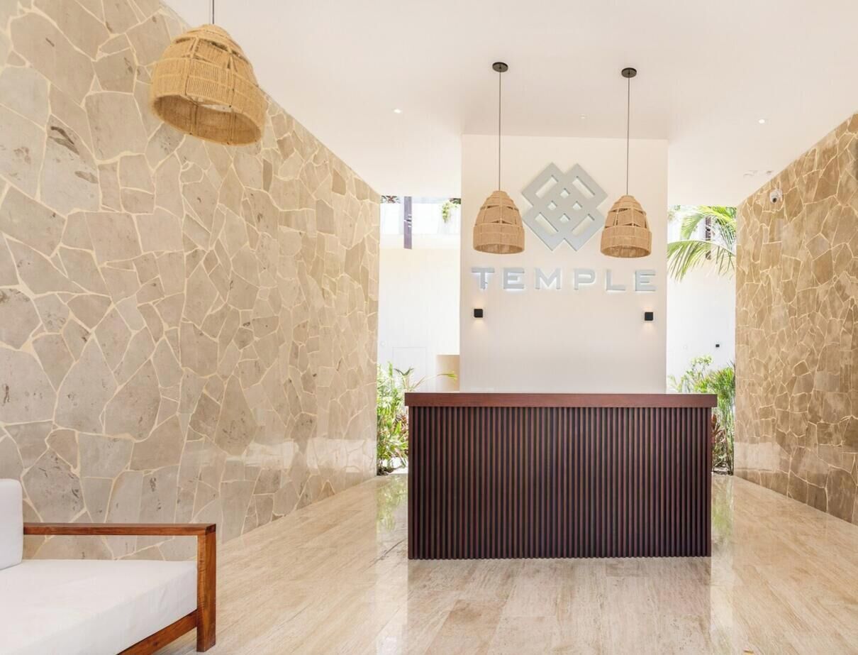 A reception area with a stone wall, a wooden reception desk, and two hanging pendant lights.