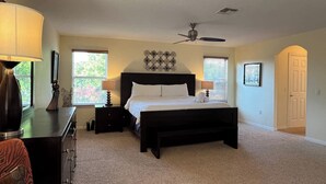 Ein Schlafzimmer mit einem großen Bett, einem Deckenventilator und einem Schreibtisch mit Lampe.