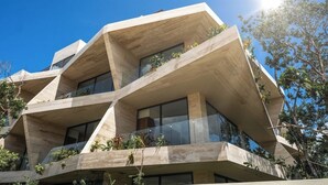 Un bâtiment moderne au design original et aux lignes angulaires, agrémenté de nombreux balcons ornés de plantes.
