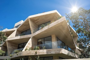 A modern building with a unique angular design, featuring multiple balconies with plants. - Marvellous Modern Studio with balcony (Tulum)