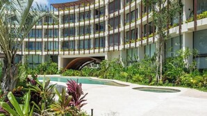 Un hôtel moderne doté de nombreux balcons, d’une piscine et d’un aménagement paysager luxuriant.