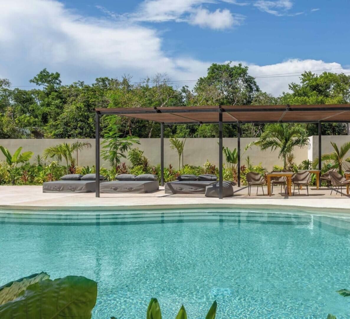 Une piscine avec des chaises longues et une pergola.