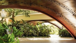 An indoor courtyard with a curved wooden ceiling, surrounded by lush greenery and a concrete floor. - Astounding Loft with Gym, Pool and Beach Shuttle (Tulum)