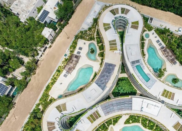 Ein Resort mit mehreren Schwimmbecken, geschwungenen Promenaden und Solaranlagen.