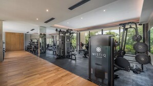 A modern gym with wooden flooring, mirrored walls, and various exercise equipment including a prominent MISTIQ TULUM machine. - Cozy Std, Steps to Infinity Pool, Shuttle to Beach (Tulum)