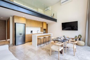 Une cuisine moderne dotée d’un îlot central, de tabourets de bar et d’une table à manger pour quatre personnes.