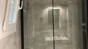 Eine begehbare Glasdusche mit Waschbecken und Pflegeprodukten.