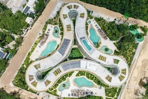 An aerial view of a resort with interconnected pools, a central building, and surrounding greenery. - 2 BD with incredible decoration and pool access (Tulum)