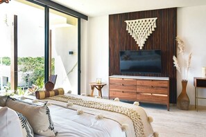 Ein modernes Schlafzimmer mit einem großen Bett, einer Holztvenzbank und Blick auf Grünflächen.