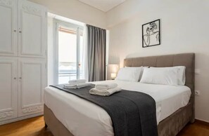 Een hotelkamer met een bed, een kledingkast, een raam met gordijnen en een aan de muur bevestigd schilderij.