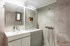 Een moderne badkamer met een grote spiegel, een witte wastafel en een douchegedeelte.