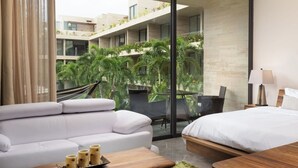A modern hotel room with a balcony, a sofa, a bed, and a dining table. - 1st Floor Sanctuary | Pool Views, Hammock and Washer (Tulum)