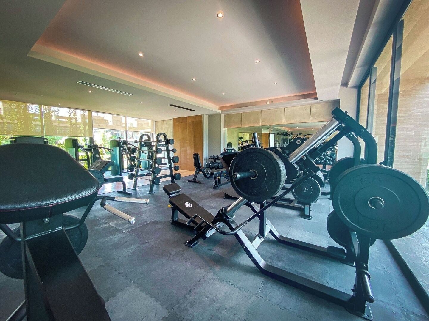 Ett gym med olika typer av träningsutrustning, inklusive styrketräningsmaskiner och lösa vikter.