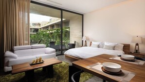A modern hotel room with a sofa, a bed, a dining table, and a view of the outdoor area. - 1st Floor Sanctuary | Pool Views, Hammock and Washer (Tulum)