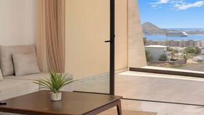 Een balkon met uitzicht op een kuststad, een bank, een bijzettafeltje en een bloempot.