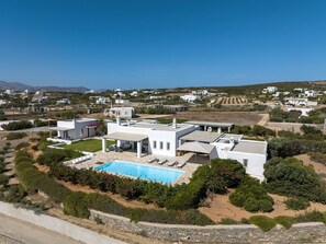 Une villa blanche dotée d’une piscine, entourée de verdure et d’autres bâtiments blancs, située dans un cadre rural.