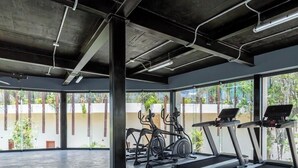 A gym with treadmills, elliptical machines, and free weights, featuring large windows and a concrete floor. - Fast Wi-Fi, private pool, A/C and jungle view! (Tulum)