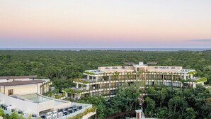 A modern resort with a central building surrounded by lush greenery and a pool area. - Fast Wi-Fi, private pool, A/C and jungle view! (Tulum)