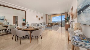 Ein modernes Wohnzimmer mit Essbereich, großen Fenstern mit Blick und einem Balkon.
