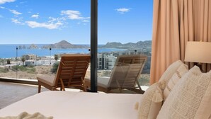 Ein Schlafzimmer mit großem Fenster, das Blick auf Strand und Stadt bietet.