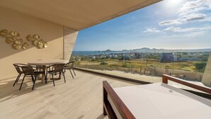 A balcony with a dining area, a view of the landscape, and a clear sky.