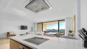 A modern kitchen with a central island, built-in oven, and a large window offering a city view.