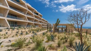 A modern hotel with multiple balconies, desert landscaping, and a view of the ocean.