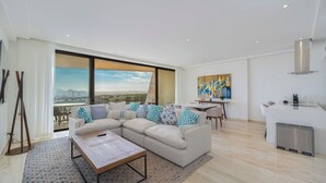 A modern living room with a sectional sofa, a dining area, and a kitchen.