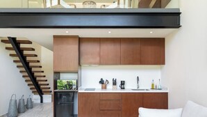 A modern kitchen with wooden cabinets, a black refrigerator, and a white countertop. - Loft w/ Private Patio, 7 Pools, Gym and WiFi and AC (Tulum)