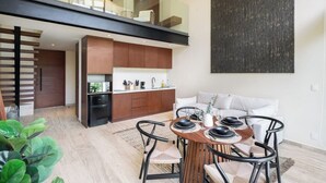 A modern apartment with a dining area, kitchen, and a loft bedroom. - Loft w/ Private Patio, 7 Pools, Gym and WiFi and AC (Tulum)