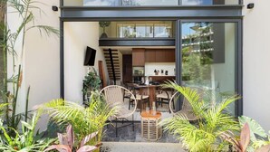 A modern house with a dining area, kitchen, and large windows. - Loft w/ Private Patio, 7 Pools, Gym and WiFi and AC (Tulum)